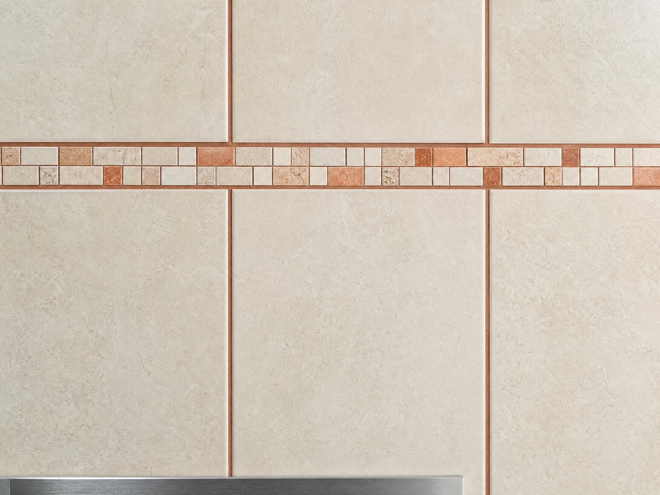 Detailed ceramic tile wall with precise grout lines and an aligned mosaic strip